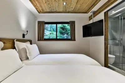 two beds in a room with a window and a tv at Chalet Black Stone in Chamonix-Mont-Blanc