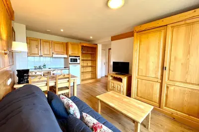 a living room with a couch and a kitchen at Reflet du Mont-Blanc in Combloux