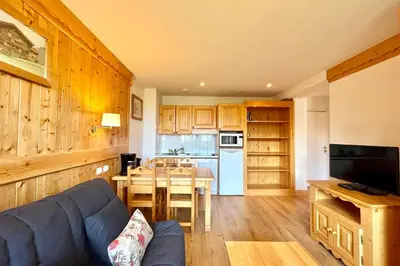 a living room with a blue couch and a kitchen at Reflet du Mont-Blanc in Combloux