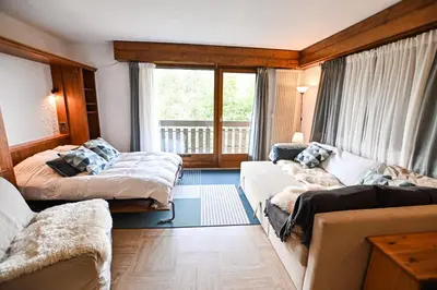 a room with two beds and a couch and a window at Panoramic Megève in Megève