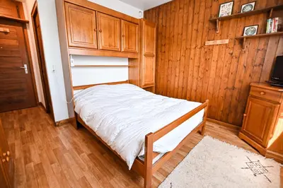 a small bedroom with a bed and wooden cabinets at Panoramic Megève in Megève