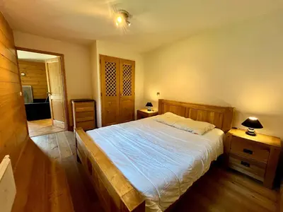 a bedroom with a large bed and a wooden floor at Appartement T2 avec grande terrasse et animaux acceptés - FR-1-624-105 in Samoëns