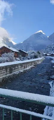 a river covered in snow next to a mountain at DOMAINE DU GRAND TETRAS SAMOENS in Samoëns