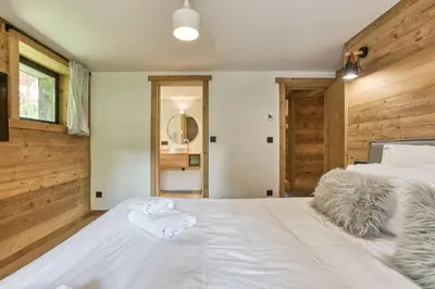 a bedroom with a large white bed with two towels at Megève - Chalet Yack - Premium jusqu'à 15 pers in Megève