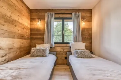 two beds in a room with a window at Megève - Chalet Yack - Premium jusqu'à 15 pers in Megève