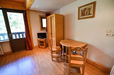 a room with a table and chairs and a door at Bright Studio With Balcony in Combloux