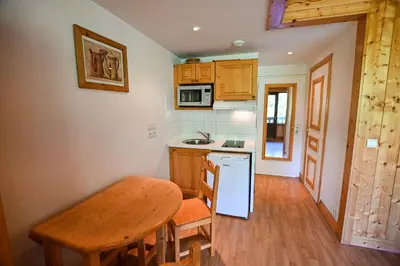 a kitchen with a wooden table and a table and a counter at Bright Studio With Balcony in Combloux