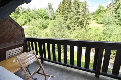 a chair on a balcony with a view of trees at Bright Studio With Balcony in Combloux