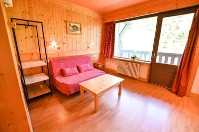 a living room with a pink couch and a table at Bright Studio With Balcony in Combloux