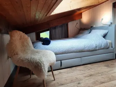 a bedroom with a bed with a chair in it at Appartement en plein centre du village (6-8 personnes) in Les Contamines-Montjoie