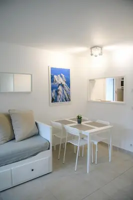 a white living room with a table and a couch at Chamonix 27 - Au Centre Vue Mont Blanc et Jardin in Chamonix-Mont-Blanc