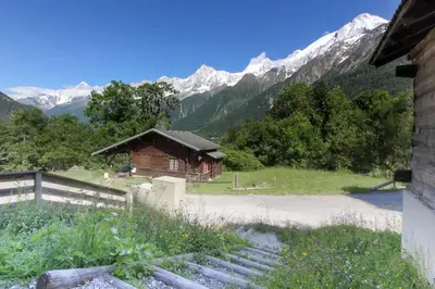 a small wooden building with snow capped mountains in the background at L'Abeille - Renovated - 4 bedroom - 8 person-110sqm - Views! in Les Houches