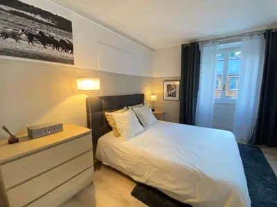 a bedroom with a white bed and a dresser and a window at Appartement Mocca au coeur de Chamonix Mont-Blanc in Chamonix-Mont-Blanc
