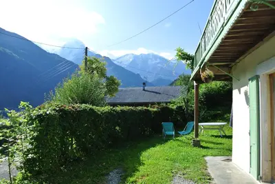 a house with a table and chairs and mountains in the background at Le Refuge in Saint-Gervais-les-Bains