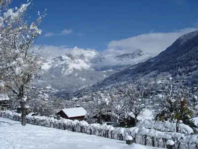 a fence covered in snow with mountains in the background at Le Refuge in Saint-Gervais-les-Bains