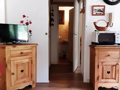 a living room with a television on a wooden cabinet at T2 calme avec parking et wifi à Chamonix - FR-1-517-64 in Chamonix-Mont-Blanc