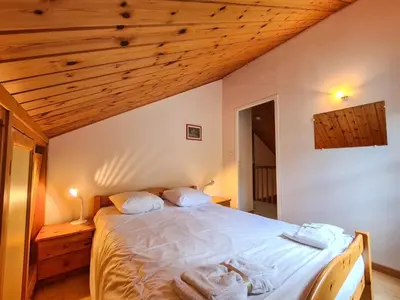 a bedroom with a bed with white sheets and wooden ceilings at Chalet lumineux avec poêle à bois et WIFI gratuit - 6 à 8 personnes - Garage - FR-1-425-117 in Flaine