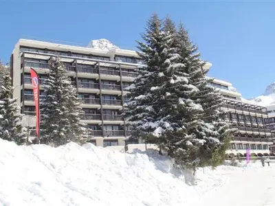 a snow covered building with trees in front of it at Appartement lumineux au pied des pistes avec piscine et spa - FR-1-425-133 in Flaine