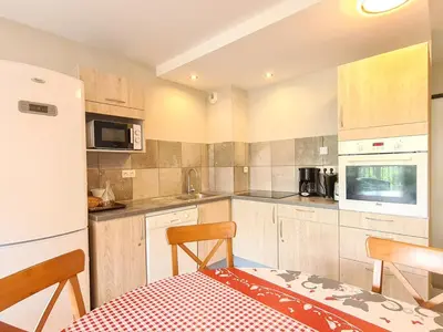 a kitchen with a table and chairs and a refrigerator at Appartement spacieux et lumineux · 8 personnes · Balcon · Flaine Centre - FR-1-425-134 in Flaine