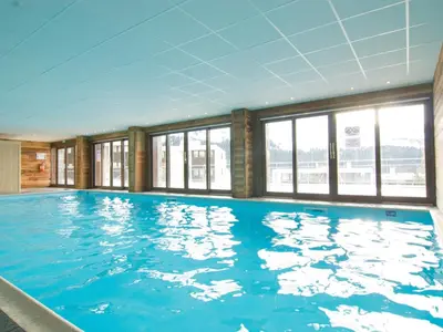 a large swimming pool with blue water in a building at Appartement confortable au pied des pistes avec piscine et parking - FR-1-425-138 in Flaine