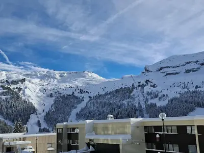 a building with a snow covered mountain in the background at Studio neuf pour 4 pers. au centre de Flaine avec balcon - FR-1-425-170 in Flaine