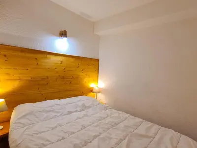 a bedroom with a white bed with a wooden wall at Studio confortable au centre station avec terrasse, animaux admis - FR-1-425-181 in Flaine