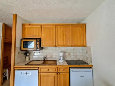 a kitchen with wooden cabinets and a sink and a microwave at Studio confortable au centre station avec terrasse, animaux admis - FR-1-425-181 in Flaine