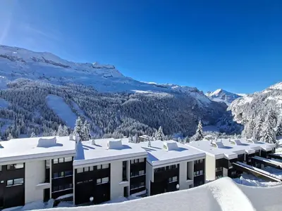a building in the snow with mountains in the background at Appartement au pied des pistes avec piscine et parking - FR-1-425-189 in Flaine