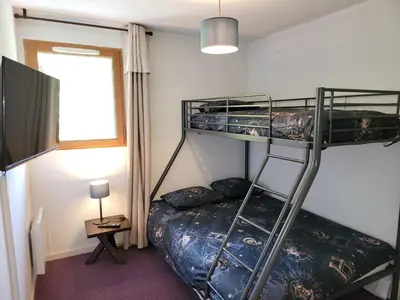 a bedroom with two bunk beds and a television at Appartement dans châlet avec piscine couverte in Saint-Gervais-les-Bains