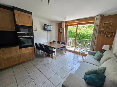 a living room with a couch and a table with chairs at Appartement dans châlet avec piscine couverte in Saint-Gervais-les-Bains
