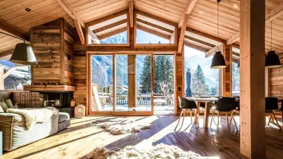 a living room with a table and a large window at Chalet du Bois in Chamonix-Mont-Blanc