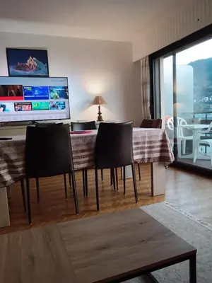 a living room with a table with chairs and a television at LE PARADISO centre SAINT-GERVAIS in Saint-Gervais-les-Bains