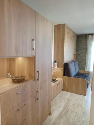 a kitchen with wooden cabinets and a blue chair at Appartement - Combloux in Combloux