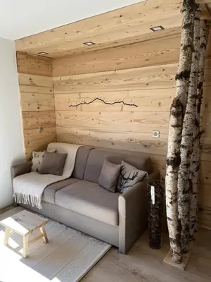 a couch in a room with a wooden wall at Le Sapin B19 Megeve - Demi Quartier in Megève