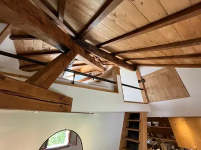 a room with wooden ceilings and a window and a ladder at un nid sous les toits in Saint-Gervais-les-Bains