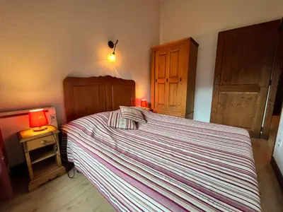 a bedroom with a bed with a striped bedspread and a lamp at Chalet 3 chambres avec piscine et parking à Samoëns - FR-1-624-111 in Samoëns