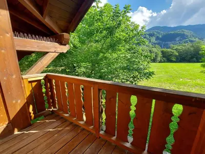 a wooden deck with a view of a green field at Chalet 3 chambres avec piscine et parking à Samoëns - FR-1-624-111 in Samoëns
