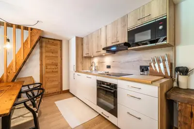 a kitchen with white cabinets and a table and a microwave at Apartment Celosia Chamonix - by EMERALD STAY in Chamonix-Mont-Blanc