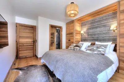 a bedroom with a large bed and wooden walls at Apache_Coudriers in Megève
