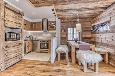a kitchen with wooden walls and a table with two stools at Chalet 3 étoiles pour 4 pers avec vue imprenable sur la vallée de Chamonix in Les Houches