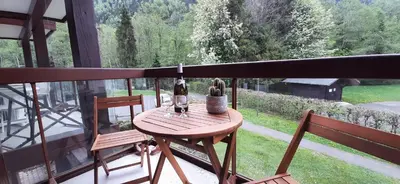 a table with two chairs and a bottle of wine on a balcony at Un havre de paix aux pieds des chemins de montagne in Les Contamines-Montjoie