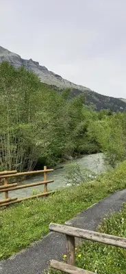 a bench on a path next to a river at Un havre de paix aux pieds des chemins de montagne in Les Contamines-Montjoie