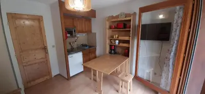 a small kitchen with a table and a refrigerator at Un havre de paix aux pieds des chemins de montagne in Les Contamines-Montjoie