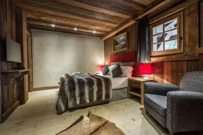 a bedroom with a bed and a couch and a chair at Chalet l'Ourson, avec jacuzzi, sauna, services hôteliers in Chamonix-Mont-Blanc