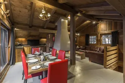 a dining room with a table and red chairs at Chalet l'Ourson, avec jacuzzi, sauna, services hôteliers in Chamonix-Mont-Blanc