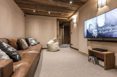 a living room with a couch and a flat screen tv at Chalet l'Ourson, avec jacuzzi, sauna, services hôteliers in Chamonix-Mont-Blanc