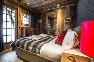 a large bed in a room with wooden walls at Chalet l'Ourson, avec jacuzzi, sauna, services hôteliers in Chamonix-Mont-Blanc