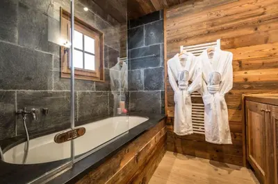 a bathroom with a bath tub and wooden walls at Chalet l'Ourson, avec jacuzzi, sauna, services hôteliers in Chamonix-Mont-Blanc