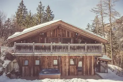 a log cabin with snow on the roof at Chalet l'Ourson, avec jacuzzi, sauna, services hôteliers in Chamonix-Mont-Blanc