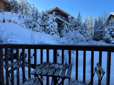 a wooden bench sitting on a porch covered in snow at Marmots Clan Megève in Megève